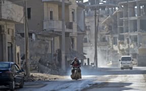 A Syrian man and a child ride a motorcycle in the Islamic State (Isis) group's former Syrian capital of Raqqa.