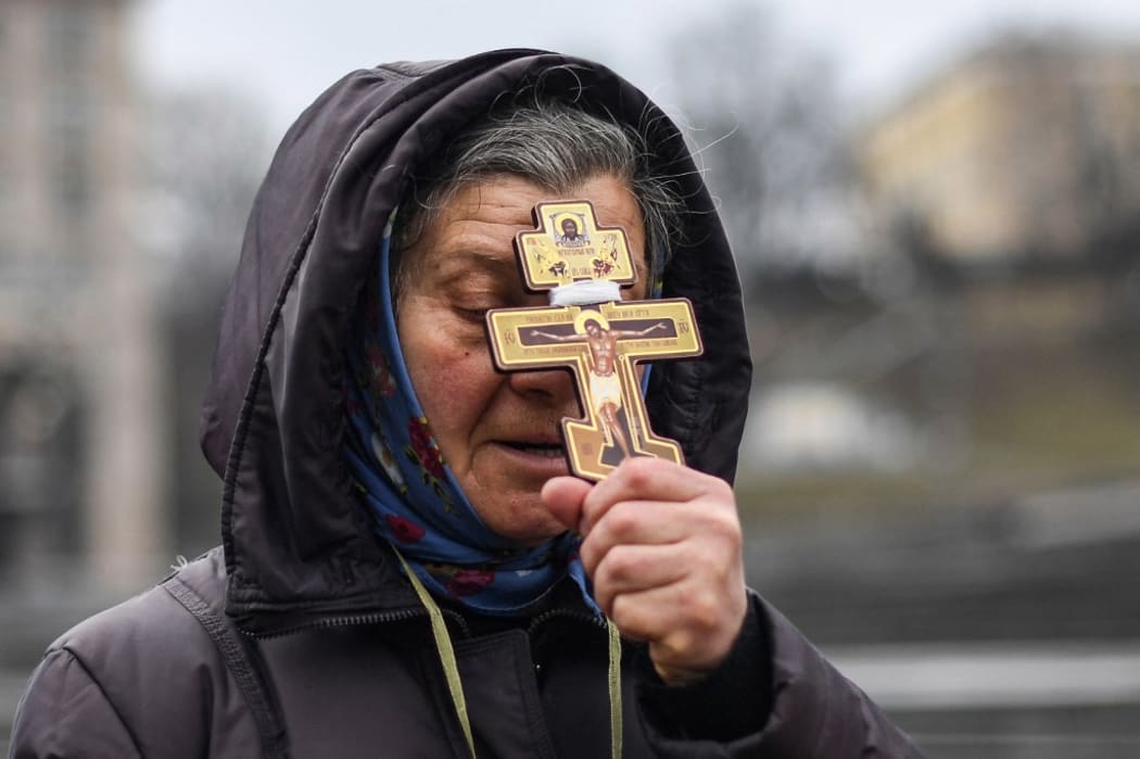 A religious woman holds a cross as she prays on Independence square in Kyiv in the morning of February 24, 2022.
Air raid sirens rang out in downtown Kyiv today