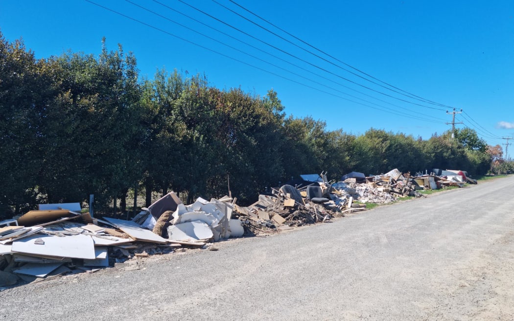 A McLeod Road resident says the council is refusing to take away piles of household rubbish that line the street because they want to test it to find out what contaminants it contains.