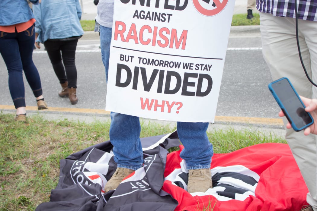A man stands on a Nazi and Anti-Fascist flag at the University of Florida in Gainesville, Florida, United States.