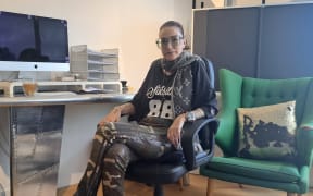 Tasha Cutton sits on a swivel chair in a casual office setting, her are legs crossed.