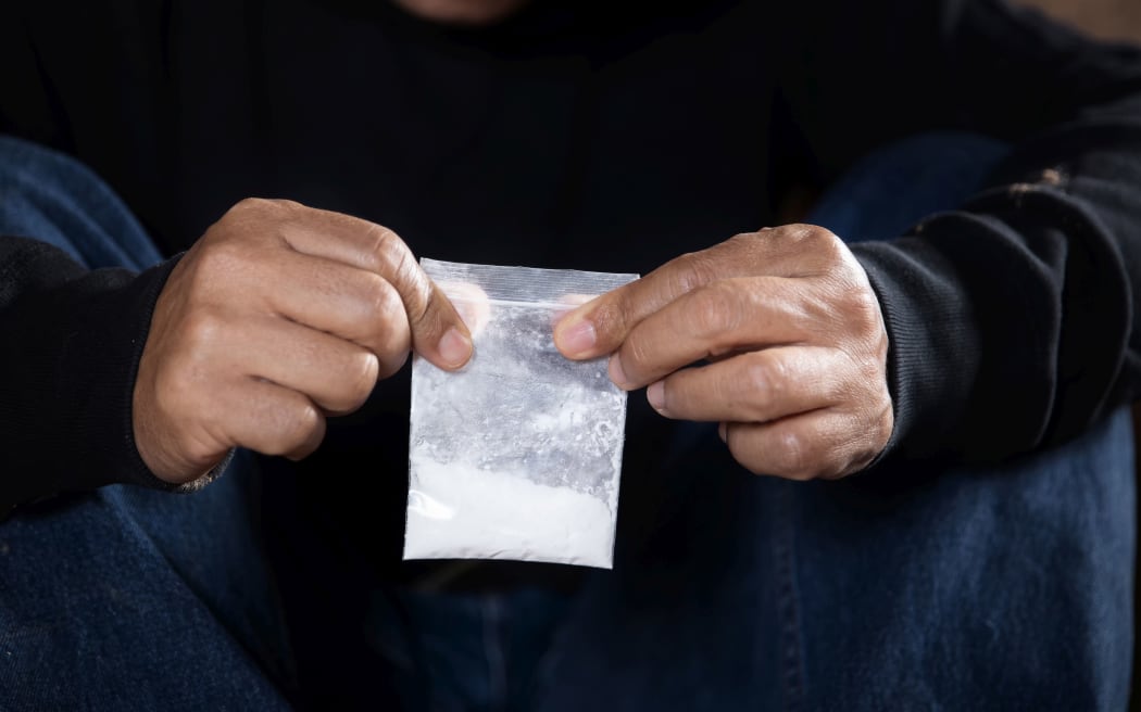 Man hand holds plastic packet or bag with cocaine or another drugs, drug abuse and danger addiction concept, selective focus, toned