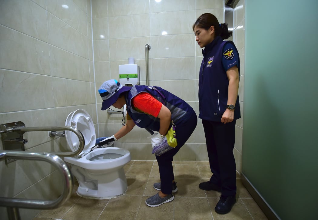 A member of Seoul city's "hidden camera-hunting" squad and a policewoman inspect a women's bathroom stall to find a "secret camera" at a museum in Seoul.