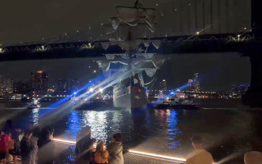 This frame grab from AFPTV footage shows a Mexican Navy training ship near the Manhattan Bridge after it slammed into the nearby Brooklyn Bridge in New York on May 17, 2025. A Mexican Navy training ship slammed into the Brooklyn Bridge late Saturday, snapping all three of its masts and igniting a rescue operation beneath the iconic New York City landmark. The Cuauhtemoc, a barque built in 1982, was damaged in the "mishap," the Mexican Navy confirmed on X, adding that the condition of those on board was "under review" by local authorities. (Photo by Cecilia SANCHEZ / AFPTV / AFP)