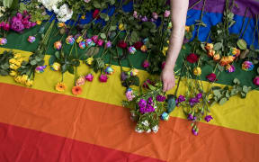 Demonstrators lay roses on a rainbow flag as they protest over a 2017 alleged crackdown on gay men in Chechnya outside the Russian Embassy in London.