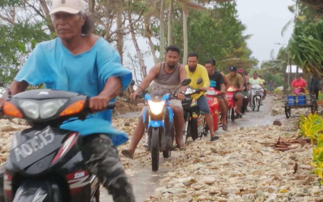 People ride their scooters through the debris washed up by Cyclone Tino on the main island, Funafuti.