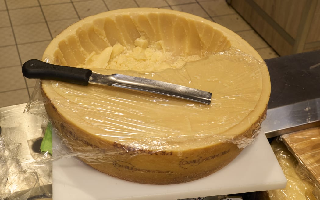 A partially cut wheel of hard, aged Italian cheese, labeled ''GRANA PADANO''