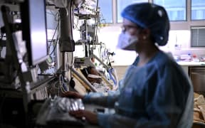 A nurse provides treatment to a Covid-19 patient under respiratory assistance, in a room of the intensive care unit of the AP-HP Cochin hospital in Paris, on March 18, 2021 as the number of people hospitalized with the Covid-19 is on the rise in the French capital.