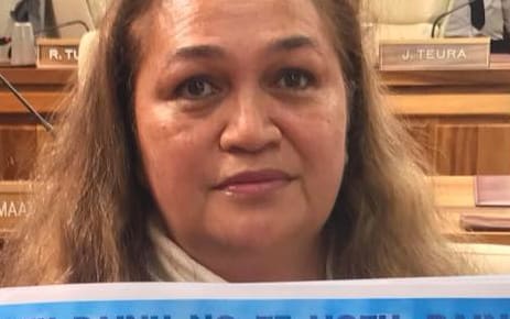 French Polynesian opposition politician Valentina Cross holds a poster expressing her opposition to a proposed floating island project.