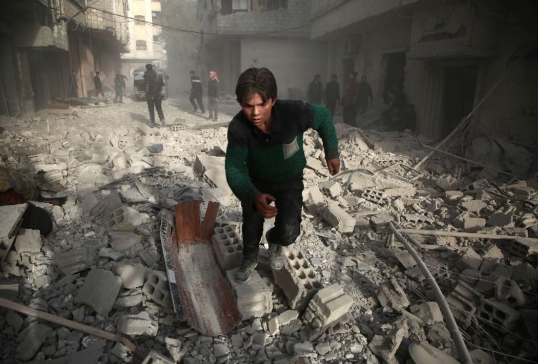 A Syrians youth runs following an air strike in the rebel-held enclave of Arbin in the Eastern Ghouta near Damascus on February 8, 2018.