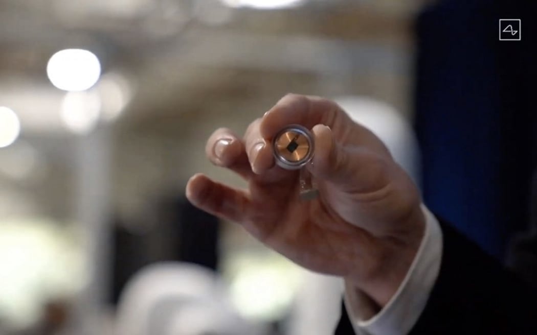 A Neuralink disk implant held by Elon Musk.
