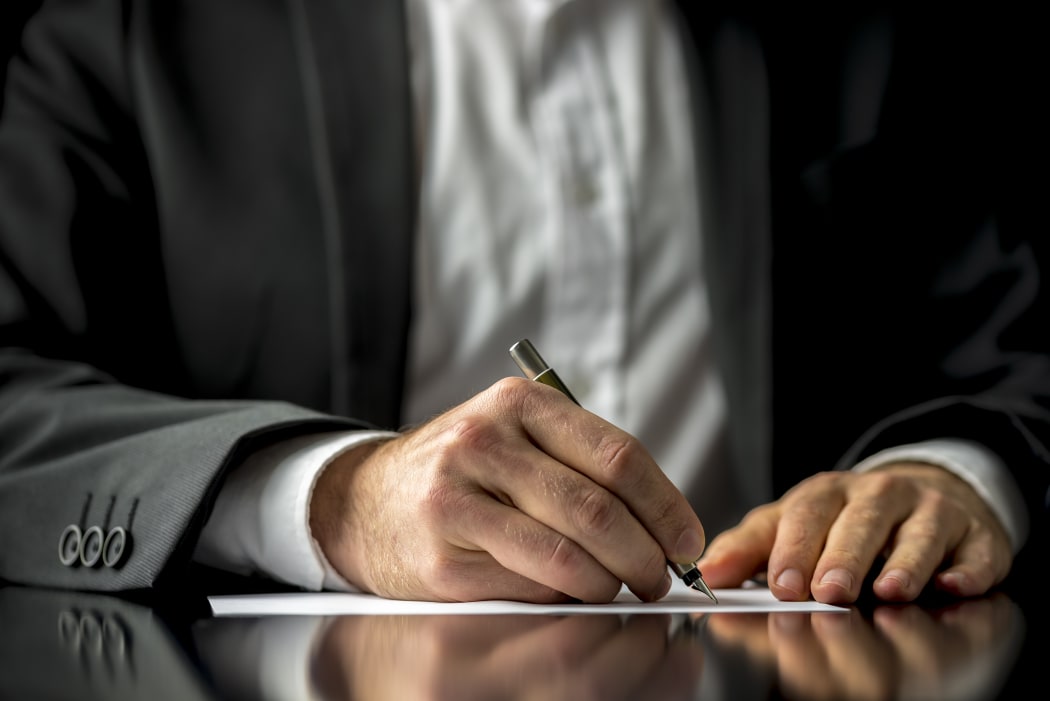 A man signing a last will and testament document.