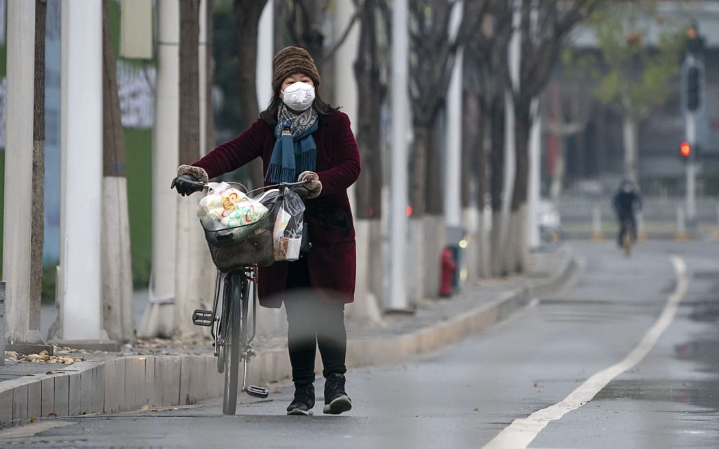 A woman wearing a mask walks along a street in Wuhan, central China's Hubei Province, on Jan. 26, 2020.