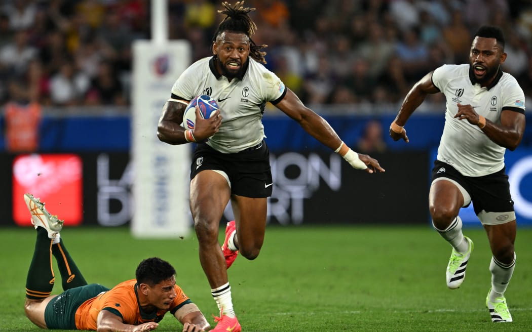 Fiji's outside centre and captain Waisea Nayacalevu, centre, runs with the ball after breaking through a tackle from Australia's centre Lalakai Foketi, left,  during the France 2023 Rugby World Cup Pool C match between Australia and Fiji at Stade Geoffroy-Guichard in Saint-Etienne, south-eastern France on September 17, 2023.