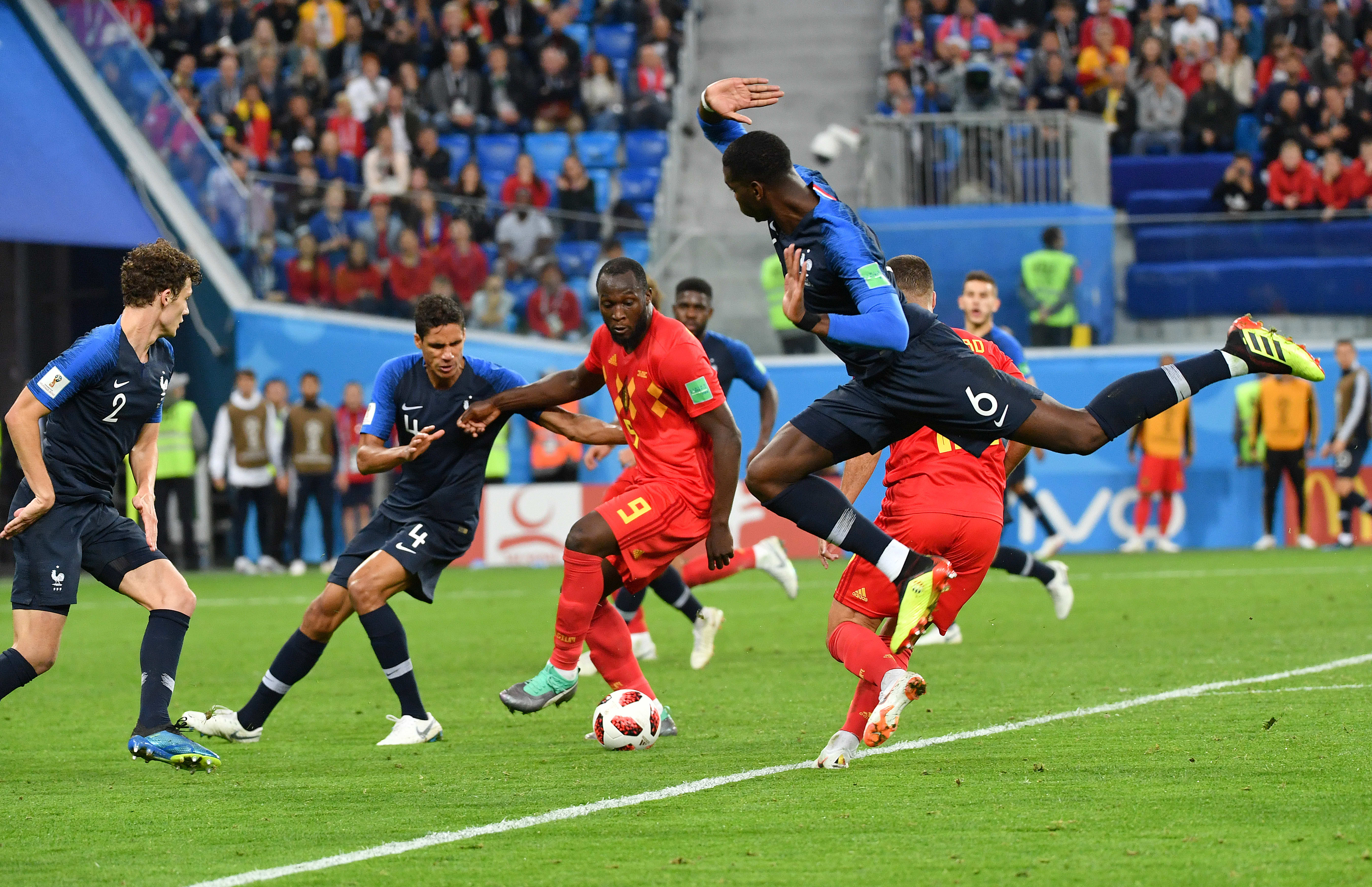 Benjamin Pavard, Raphael Varane, Romelu Lukaku, and Paul Pogba in action in a France vs Belgium match.