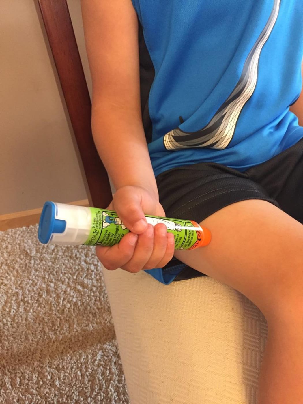 A young boy demonstrates how to use an EpiPen to treat anaphylaxis.