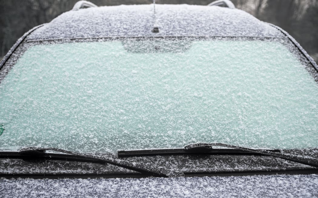 frozen windshield of a car with ice and snow, concept of traffic risks in winter, copy space, selected focus