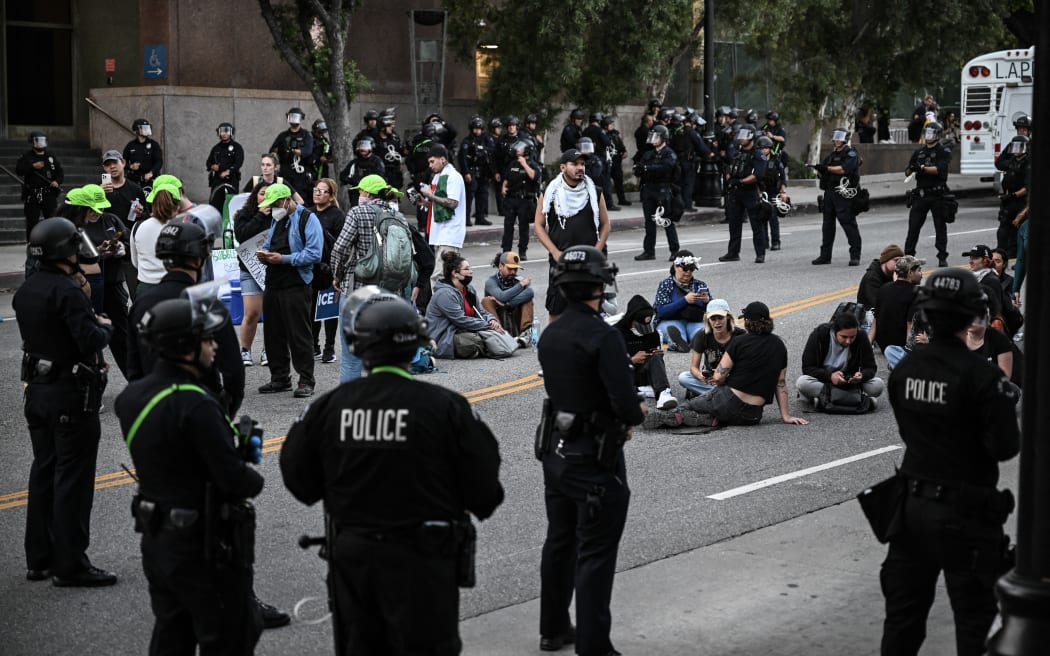 Police officers surround arrested protesters following a demonstration against federal immigration operations near Los Angeles City Hall in Los Angeles on June 11, 2025. Over 1,000 people massed in America's second biggest city for a sixth day of protests, with the crowd peaceful as they marched through the streets. A second night of curfew was in place as city leaders try to get a handle on the after-dark vandalism and looting that scarred a few city blocks in the 500-square-mile (1,300 square kilometers) metropolis. (Photo by RONALDO SCHEMIDT / AFP)