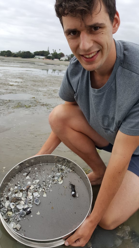 Kurt Squires holds a sieve containing all the material larger than 2mm across, from a core of sand and mud collected from Manukau Harbour.