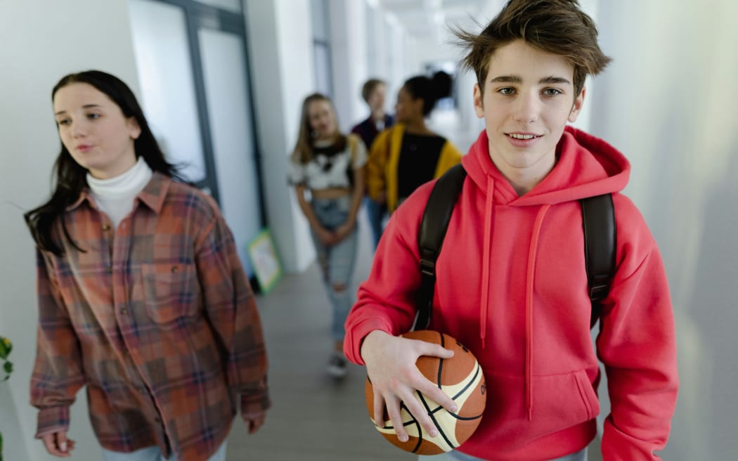 A group of high school students not wearing uniforms walking through the corridors of a hallway.