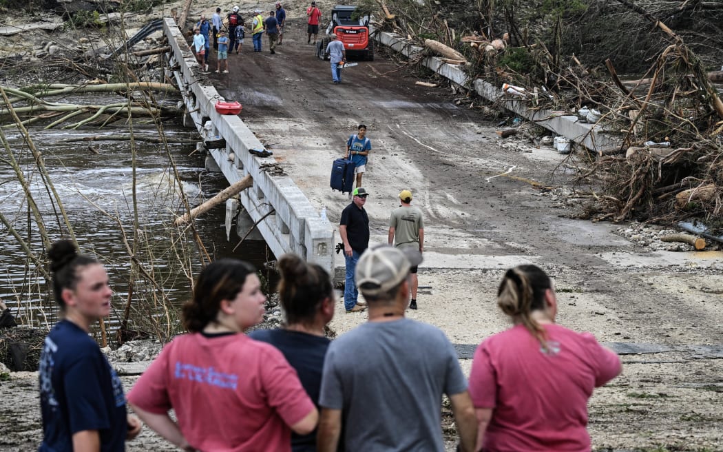 People look on as law enforcement and volunteers continue to search for missing people near Camp Mystic, the site of where at least 20 girls went missing after flash flooding in Hunt, Texas, on July 5, 2025. Rescuers were on Saturday searching for more than 20 girls missing from a riverside summer camp in the US state of Texas, after torrential rains caused devastating flooding that killed at least 27 people -- with more rain on the way. "So far, we've evacuated over 850 uninjured people, eight injured people and have recovered 27 deceased fatalities at this time. Of these 27, 18 are adults, nine are children," said Kerr Country Sheriff Larry Leitha on July 5. (Photo by RONALDO SCHEMIDT / AFP)