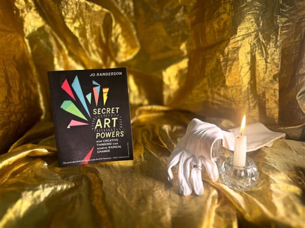 A book is presented on a yellow silk sheet with a candle and white glove nearby.