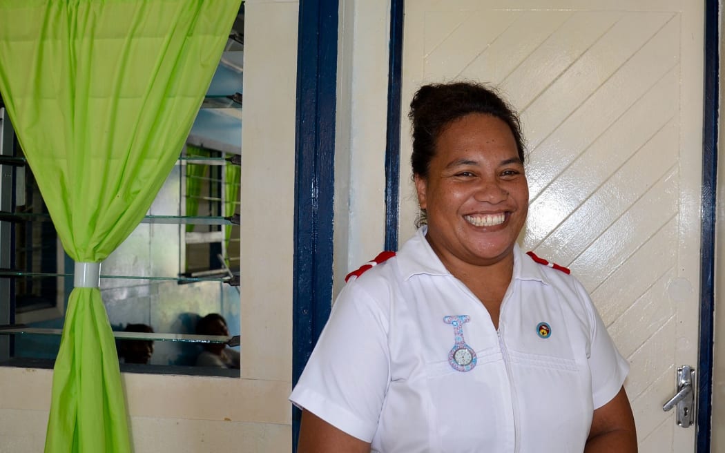 Nurse stands smiling in white uniform