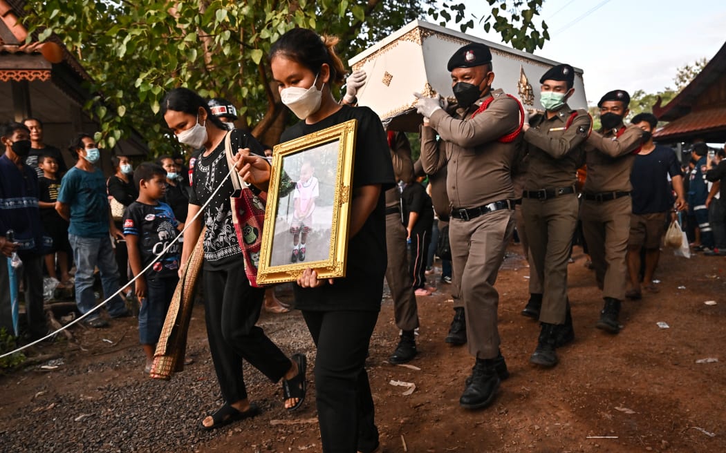 Relatives walk with a portrait and the coffin of a victim of the nursery mass shooting during the cremation ceremony in Na Klang in northeastern Nong Bua Lam Phu province on October 11, 2022.