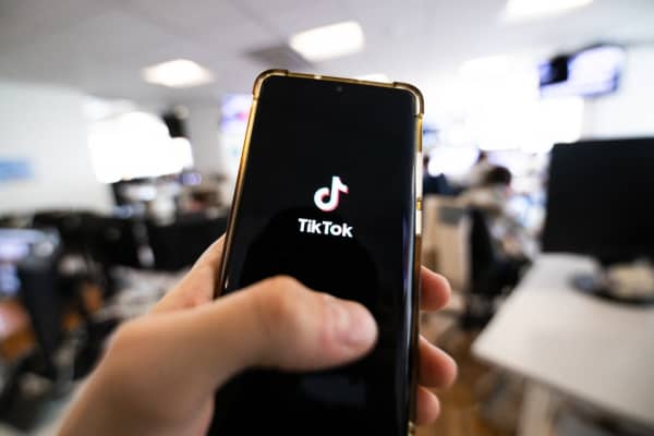 This photograph taken on April 19, 2024 shows a man holding a smartphone displaying the logo of Chinese social media platform Tiktok in an office in Paris (Photo by Antonin UTZ / AFP)
