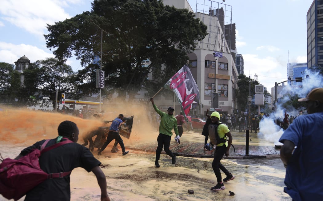 Protesters scatter as Kenya police spray water canon at them during a protest over proposed tax hikes in a finance bill in downtown Nairobi, Kenya Tuesday, June. 25, 2024. (AP Photo/Brian Inganga)
