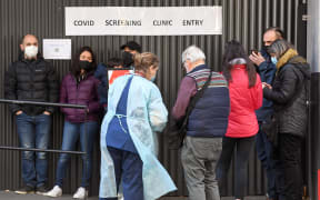 A medical worker speaks to people queueing for coronavirus testing at The Royal Melbourne Hospital on 16 July.