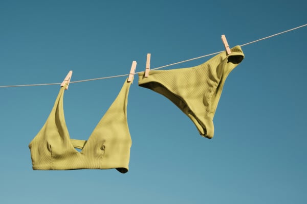 A green bikini pegged on a washing line against a blue sky.