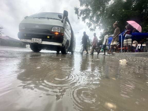 Commuters jump over a puddle to board a bus at Point Cruz in the Solomon Islands capital Honiara. 16 April 2024