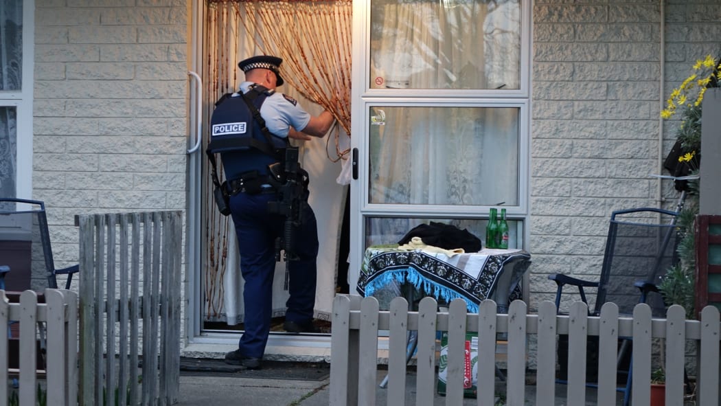 A police officer at the flat in the Christchurch suburb of Hei Hei where a man was shot in the leg.