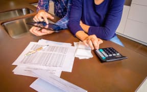 Closeup of young couple reviewing their bank accounts with a digital tablet and calculator at home. Financial family concept.