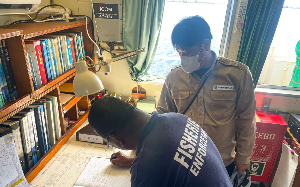 Fisheries monitoring and compliance officer Stevenson Graham reviews the log of a purse seiner during a routine boarding and inspection by Marshall Islands Marine Resources Authority officers. Photo: Francisco Blaha.