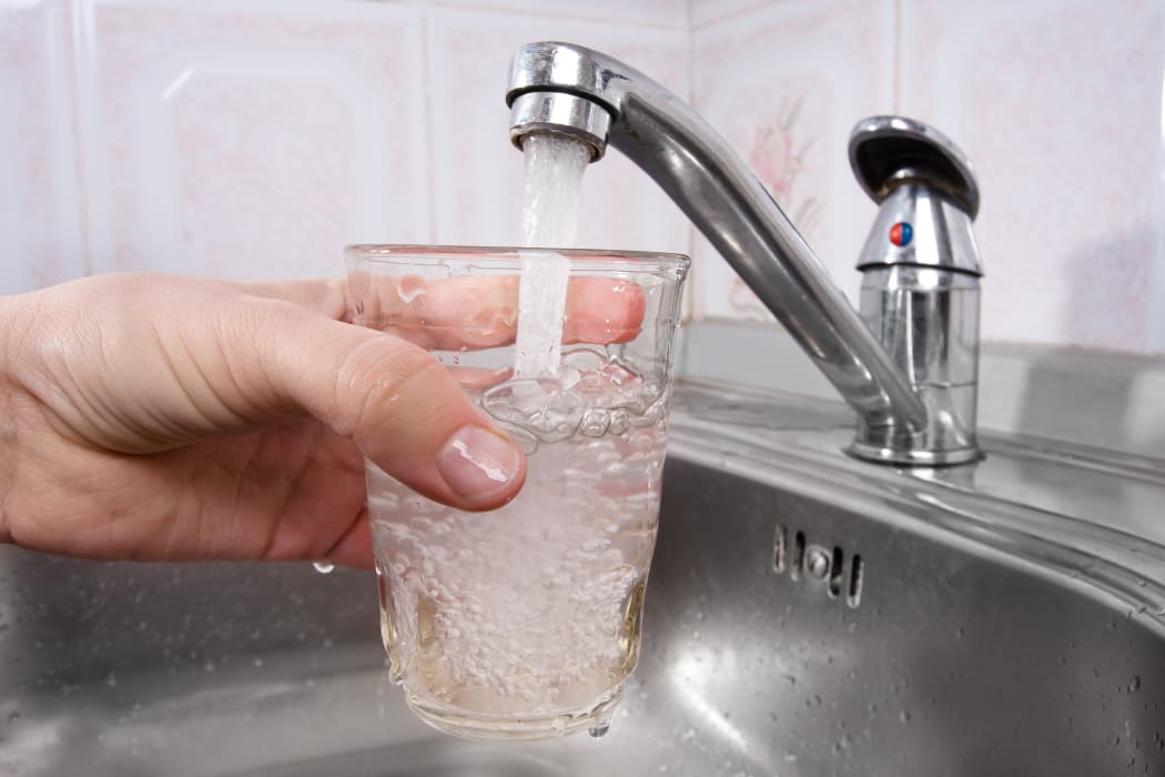A glass is filled with drinking water from a tap