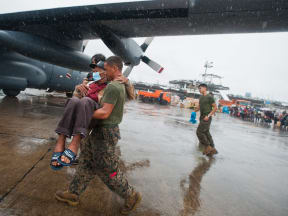 New Zealand personnel help survivors onto an aircraft.