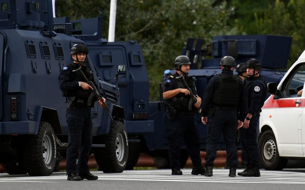 Kosovo's police officers stand guard at the entrance of the village of Banjska on September 24, 2023, after one policeman was killed and another wounded in north Kosovo early Sunday. According to authorities, the incident occurred during an armed attack on a police patrol as it approached a blocked road near the border with Serbia. (Photo by STRINGER / AFP)