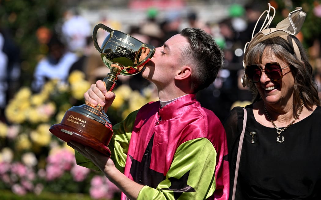 Irish jockey Robbie Dolan kisses the trophy next to New Zealand expariate trainer Sheila Laxon after Knights Choice won the 2024 Melbourne Cup at Flemington racecourse, November 5, 2024. (Photo by William WEST / AFP) / --IMAGE RESTRICTED TO EDITORIAL USE - STRICTLY NO COMMERCIAL USE)