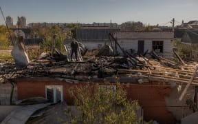 A man stands on a roof of a house that was damaged during an overnight Russian attack, in the southern city of Kherson, on October 30, 2023, amid the Russian invasion of Ukraine. (Photo by Roman PILIPEY / AFP)