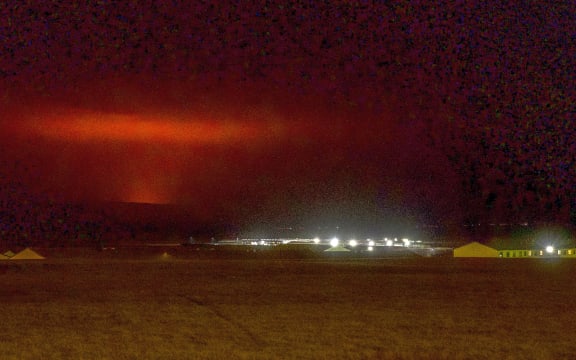 The red shimmer from magma is seen coming out from the erupting Fagradalsfjall volcano behind the town of Keflavik, in Iceland.