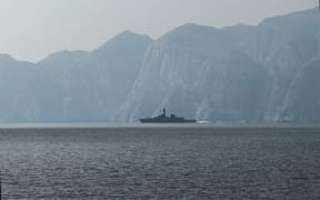 A navy vessel is seen sailing in the Strait of Hormuz, a vital waterway through which much of the world's oil and gas passes on March 1, 2026. Two ships were attacked in the Strait of Hormuz on March 1, maritime security agencies said, as Iran pressed a second day of strikes in response to US-Israeli military strikes on Iran killing it's supreme leader. (Photo by Sahar AL ATTAR / AFP)