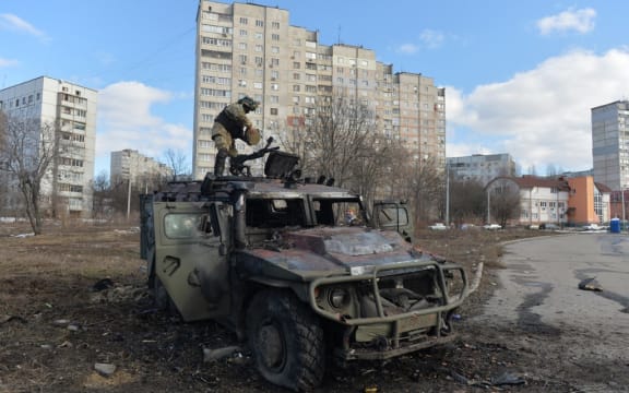 A Ukrainian Territorial Defence fighter examines a destroyed Russian infantry mobility vehicle GAZ Tigr after fighting in Kharkiv. Ukrainian forces secured full control of Ukraine's second biggest city on 27 February, 2022, following street fighting with Russian troops, the local governor said.