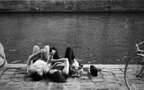 A couple lying down by a river.