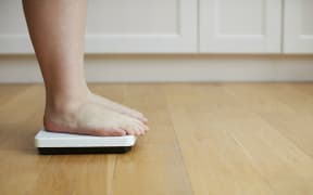 Woman standing on weighing scales. (Photo by Science Photo Library / R3F / Science Photo Library via AFP)