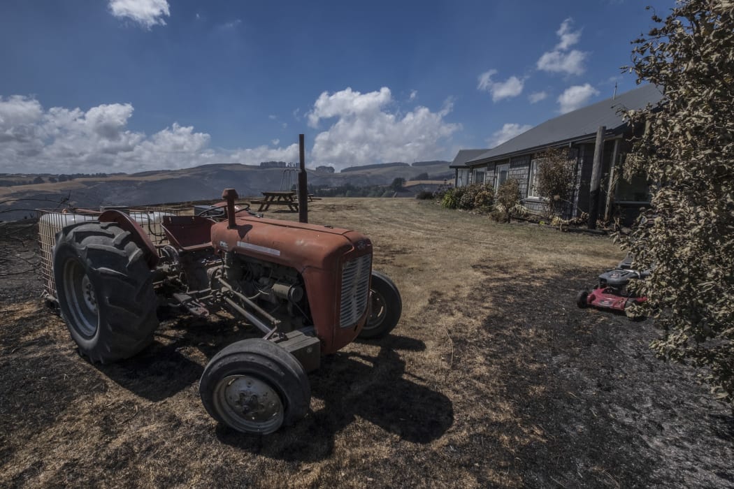 A tractor stands nearly intact after fire raged around this property in the Port Hills