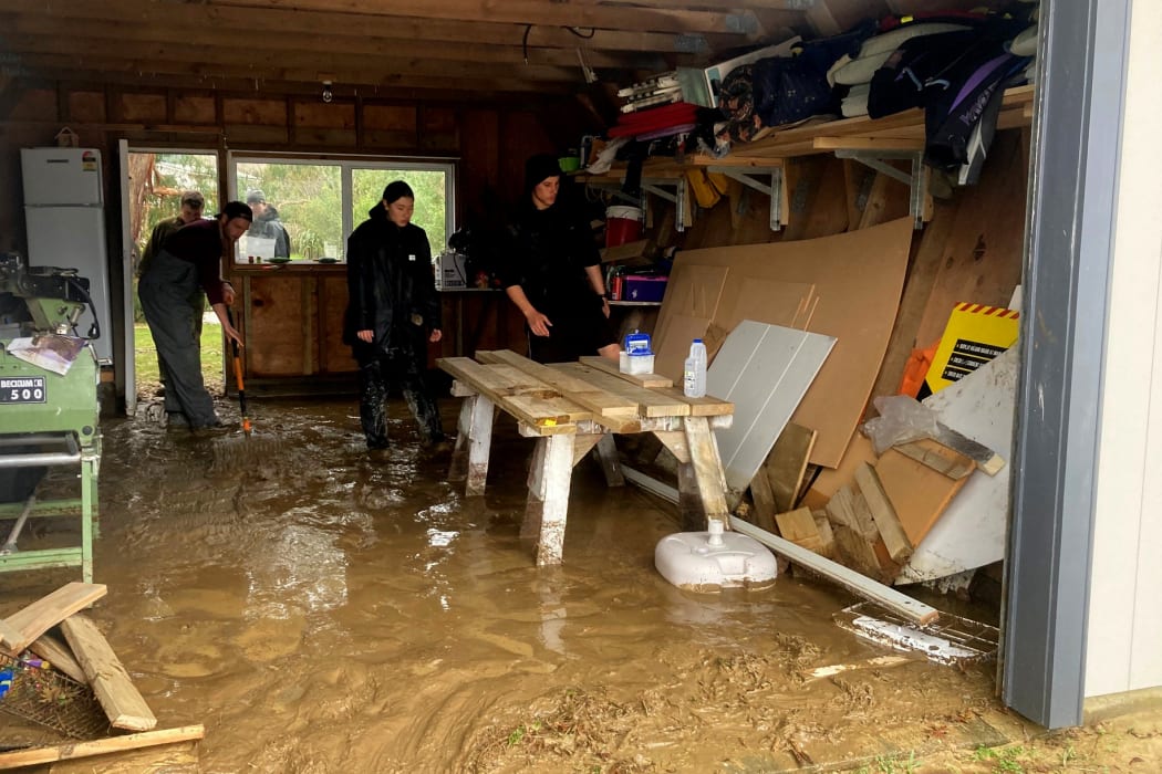 Students clean the inside of a resident’s garage after it flooded.