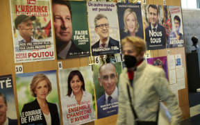 A woman passes posters of candidates as French citizens arrive to cast their vote in the presidential election at the Lycée Français in New York City on April 09, 2022.