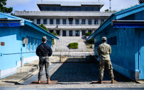 United Nations Command soldiers (right) and a South Korean soldier (left) stand guard before North Korea's Panmon Hall and the military demarcation line separating North and South Korea, at the Joint Security Area of the Demilitarized Zone on October 4, 2022.